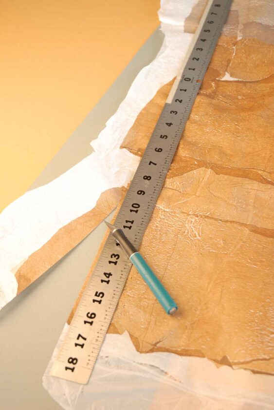 Using a straightedge and a craft knife, trim plastic fabric to about 9 by 30 inches.